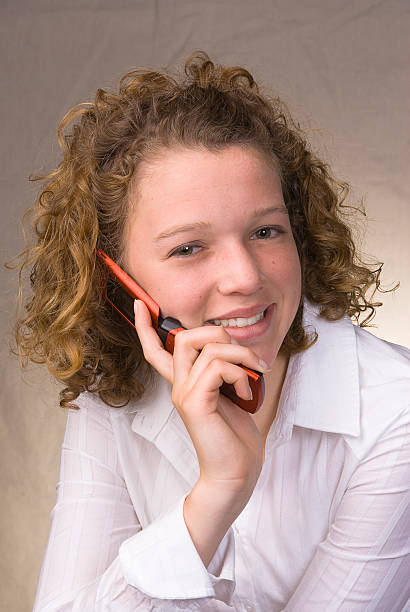 Smiling teenage girl talking on cell phone stock photo