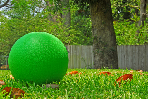 Bright green kickball on grass in summer yard