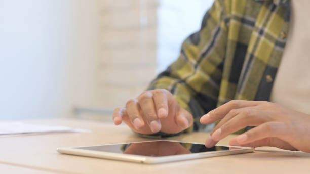 istock Close Up of African Man Using Tablet Lying on Desk 1458499910