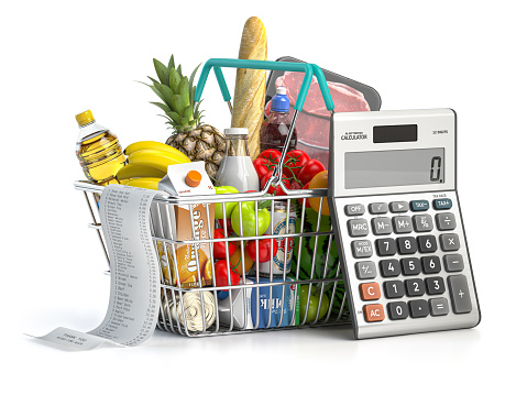 Cesta de la compra llena de comida de comestibles con recibo y calculadora aislados en blanco. Concepto de presupuesto del hogar, ahorro, inflación y consumismo. photo