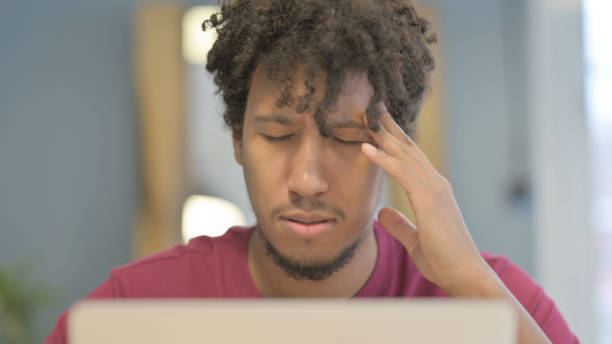 istock Close Up of African Man having Headache while Working on Laptop 1458502248