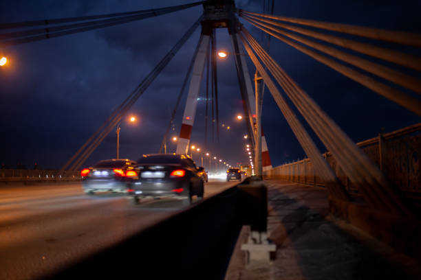 29.11.2022, Cherepovets, Russia. A large automobile bridge on which cars drive at night. A bridge with large columns and lighting. Cars are driving over the bridge