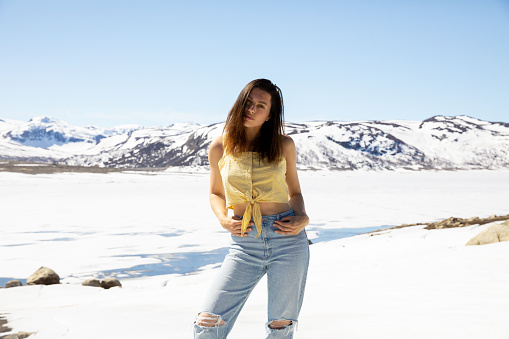 A young woman standing in the snow on a warm spring day in Norway