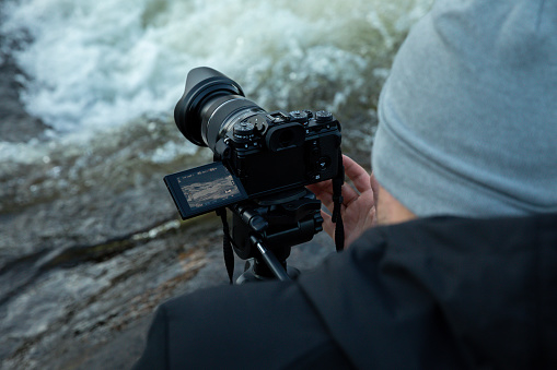 A man operating his video camera taking a shot of a river in norway