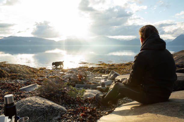 A man sitting at a campfire enjoying the sunset