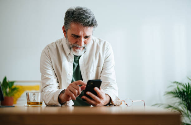 istock Smiling Mature Businessman Using A Mobile Phone At Home 1458505663