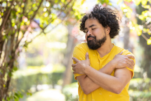istock young Mexican man with beard and afro hugging himself, self love concept 1458506642