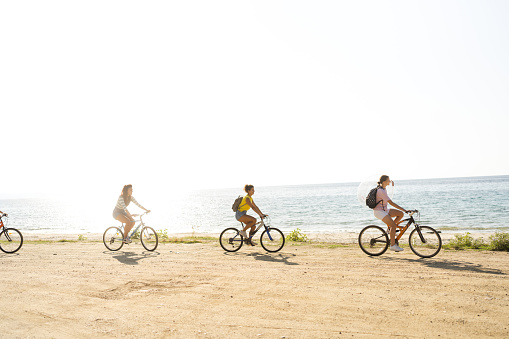 Photo of a smiling teenage girls, using bicycles to commute to the beach