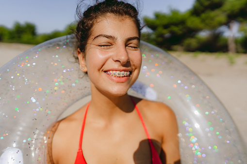 Photo of a smiling teenage girl with braces enjoy sunny summer afternoon at the beach