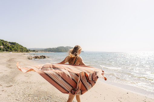 Photo of a young teenage girl walking down the beach, sunbathing, and enjoy warm summer breeze