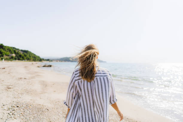 istock Young woman walking down the beach 1458509134