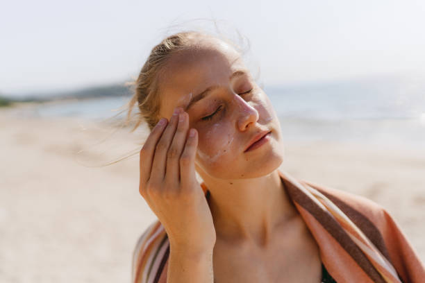 Teenager trägt Sonnencreme am Strand auf – Foto