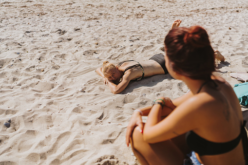 Photo of a two teenage girl sunbathing at the beach.