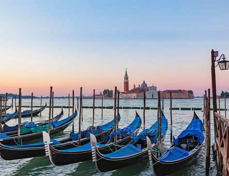 Beautiful view of traditional Gondolas on Canal Grande with historic Basilica di Santa Maria della Salute in the background on a sunny day in Venice, Italy