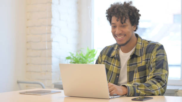 istock African Man Cheering Results on Laptop in Office 1458512393