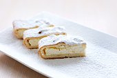 cheesecake curd strudel sliced on white plate sprinkled with powdered sugar dough is separated from curd creating drawing place for text advertising benefits of cooking show recipes restaurant serving