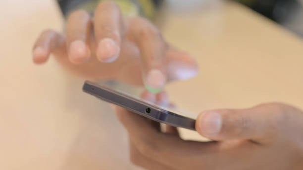 istock Close up of African Man Browsing Internet on Smartphone 1458513166