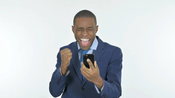 istock African Businessman Celebrating on Smartphone on White Background 1458516549