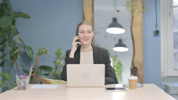 istock Businesswoman Talking on Phone while using Laptop 1458517761