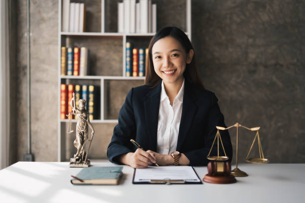 Attractive young lawyer in office Business woman and lawyers discussing contract papers with brass scale on wooden desk in office. Law, legal services, advice, Justice and real estate concept. atractiva joven abogada en la oficina mujer de negocios y abogados discutiendo documentos de contrato con escala de latón en el escritorio de madera en la oficina. derecho, servicios jurídicos, asesoramiento, justicia y concepto inmobiliario.