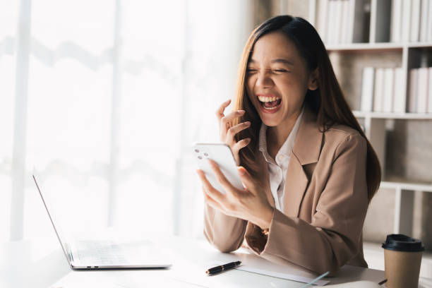 istock Cheerful young business woman talking on phone working in modern office. 1458518924