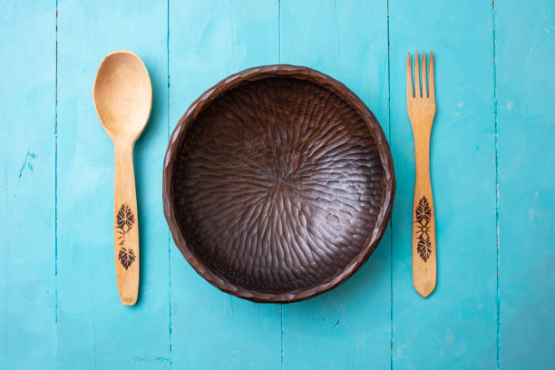 Wooden fork, spoon and sculpted bowl on acrylic painted blue boards background