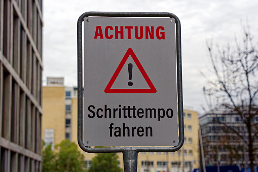 Warning traffic sign with text Achtung Schritttempo fahren, translation is attention drive walking pace at City of Zürich on a cloudy winter noon.