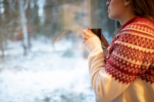 istock A woman is standing by the window drinking tea 1458524764
