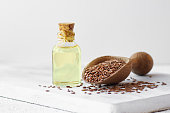 Glass bottle of linseed or flaxseed oil with flax seeds on rustic table, oil dietary fiber background