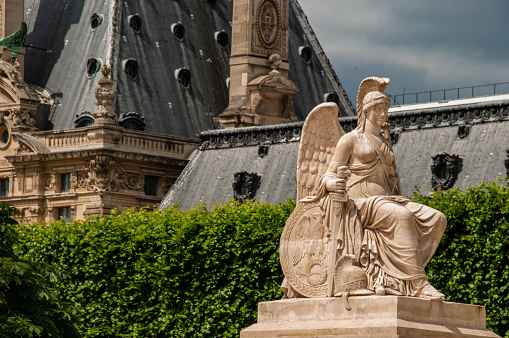 A statue of a woman holding a sword with angel wings in the courtyard of the Louvre Museum the City of Paris during the summer