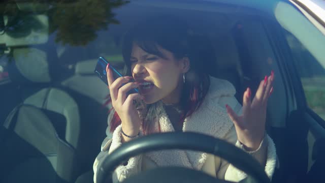 Portrait of annoyed lady arguing on smartphone in modern car. Aggressive woman talking on mobile phone in a car. Stressed  woman getting angry in automobile.