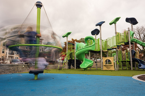 Motion blur shows kids spinning rapidly on playground equipment.