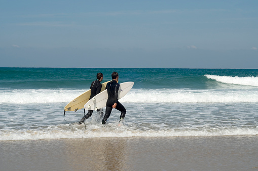 two surfers getting in the water
