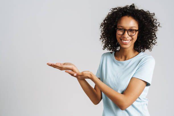 istock Black curly woman wearing eyeglasses smiling and holding copyspace 1458532030