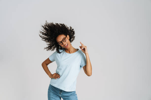 istock Black curly woman wearing eyeglasses laughing while dancing on camera 1458532754