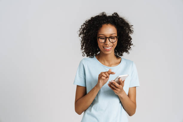 istock Black curly woman wearing eyeglasses smiling and using cellphone 1458534176