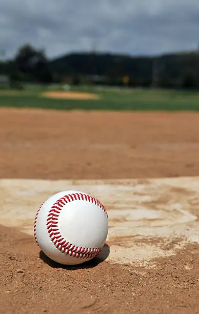 A baseball near home plate with field in background.