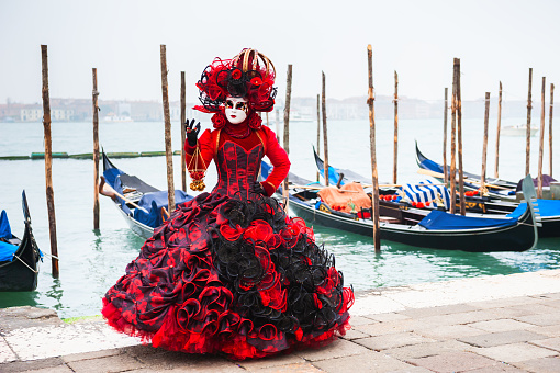 Venice, Italy - March 01, 2022: Woman dressed in traditional costume, in Riva degli Schiavoni waterfront, part of the Venice Mask Carnival, Veneto, Italy