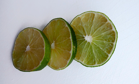 Persian lime fruit slices on an white cutting board. Lime is a citrus fruit. This lime is a cross between key lime and lemon