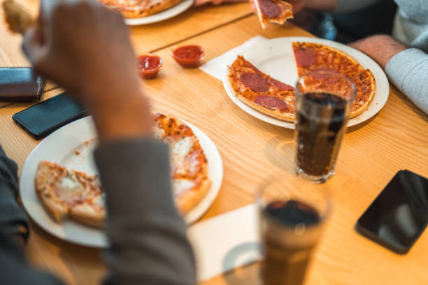 Table view when diverse group of friends hanging out and catching up in a local bar. Eating pizza and drinking soft drinks.