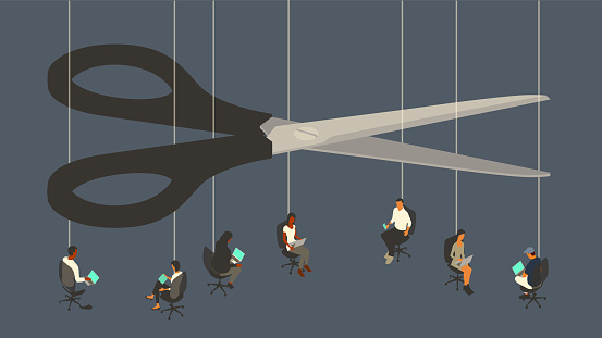Layoffs are illustrated by an oversized pair of scissors, that looms over seven workers sitting in office chairs suspended by strings. Employees use their laptop computers and mobile devices, but some of their jobs could be cut at any time, as they are shown hanging by a thread. Their jobs are on the line. Conceptual illustration uses a flat, limited color palette over a dark blue background, presented in isometric view on a 16x9 artboard.