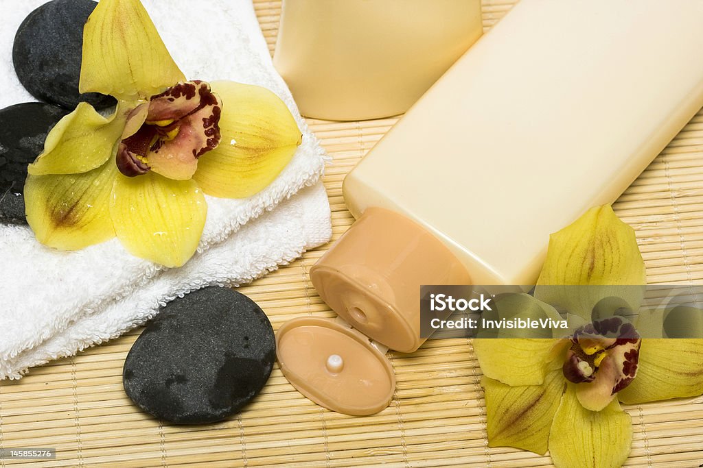 Giallo bottiglia di shampoo per capelli con asciugamano e orchidea - Foto stock royalty-free di Accessorio personale