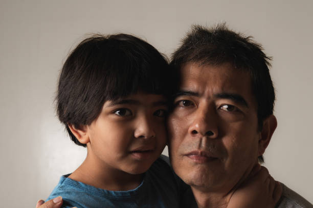 Close-up portrait of father and son looking at camera