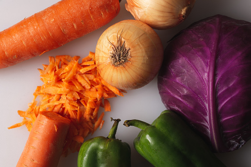 Assorted vegetables viewed from above, over a white background