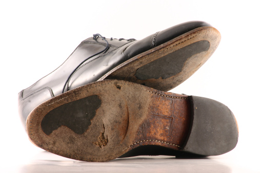 Well worn, old dress shoes. Hole in bottom, cracking leather, worn out sole. Black shoes on white background. See Similar photos in lightbox - click link below (old & new - old vs. new).