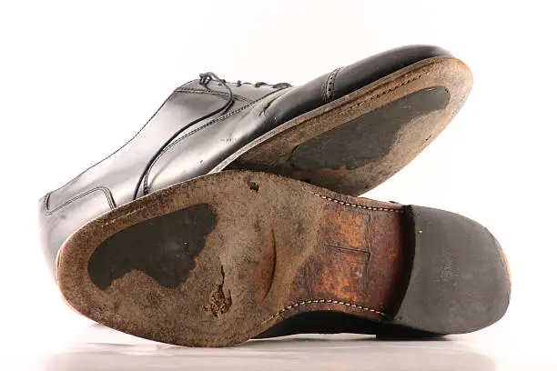 Well worn, old dress shoes. Hole in bottom, cracking leather, worn out sole. Black shoes on white background. See Similar photos in lightbox - click link below (old & new - old vs. new).