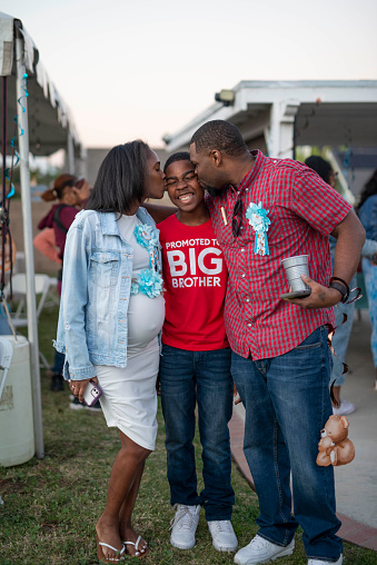 Parents kissing son at baby shower