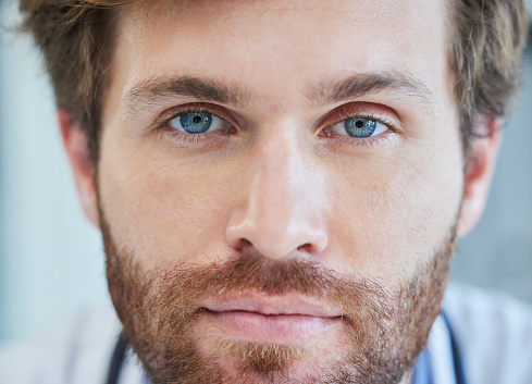 Doctor, face and blue eyes in healthcare, medical or surgeon with vision for results at the hospital. Closeup portrait of male nurse professional head or optician ready for eye care or surgery
