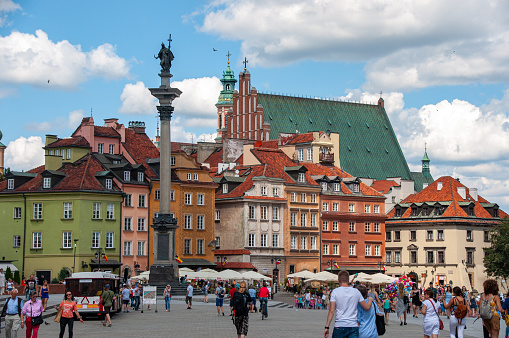 People enjoy the city of Warsaw on a beautiful summer day. Shops, restaurants and residential buildings fill the scene with pedestrians in the foreground