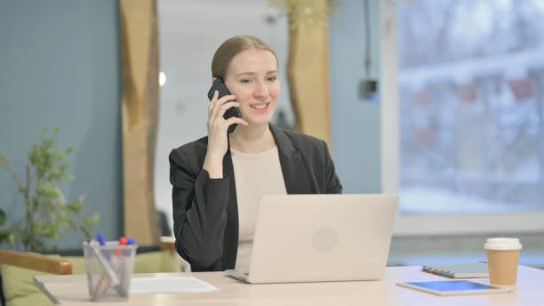 istock Businesswoman Talking on Phone while using Laptop 1458566037